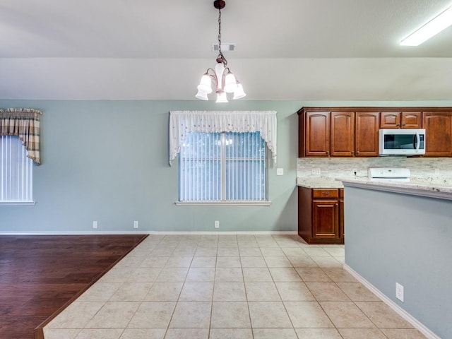 kitchen featuring light countertops, a chandelier, pendant lighting, range, and light tile patterned floors