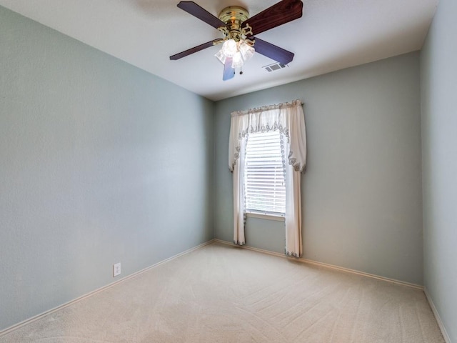 spare room with light colored carpet, a ceiling fan, and baseboards