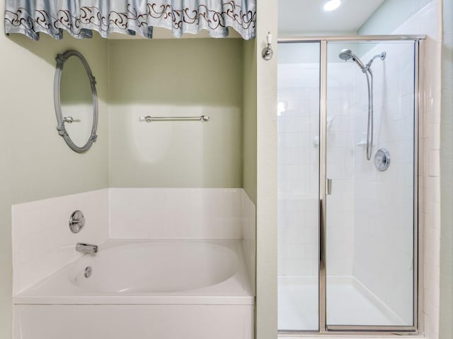 bathroom featuring a stall shower and a bath