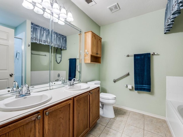 bathroom featuring baseboards, tile patterned flooring, a garden tub, double vanity, and toilet