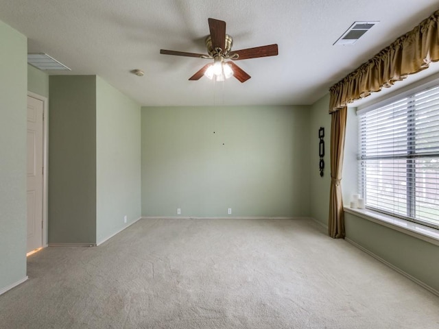 empty room featuring light carpet, a ceiling fan, and baseboards