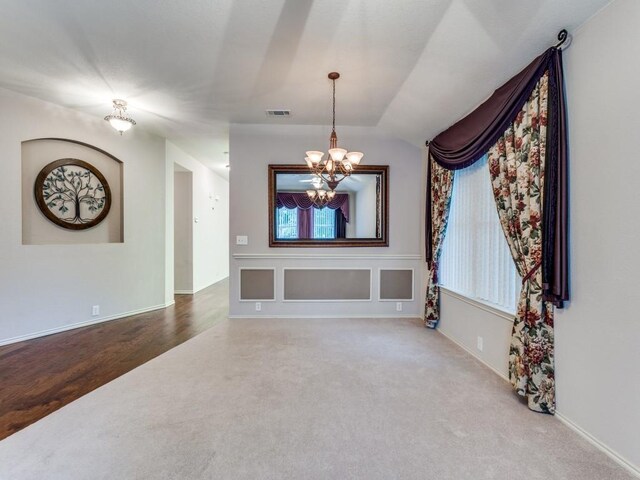 spare room featuring carpet flooring, a chandelier, baseboards, and vaulted ceiling