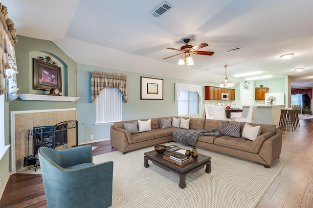 living area with wood finished floors, ceiling fan, a chandelier, a tile fireplace, and baseboards
