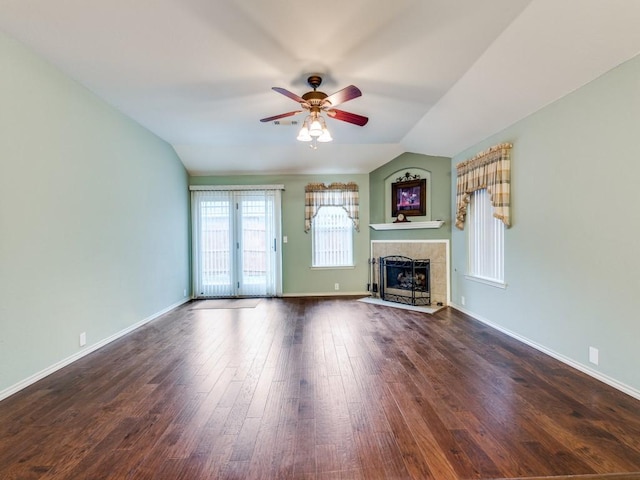 unfurnished living room with a ceiling fan, a tiled fireplace, wood finished floors, lofted ceiling, and baseboards