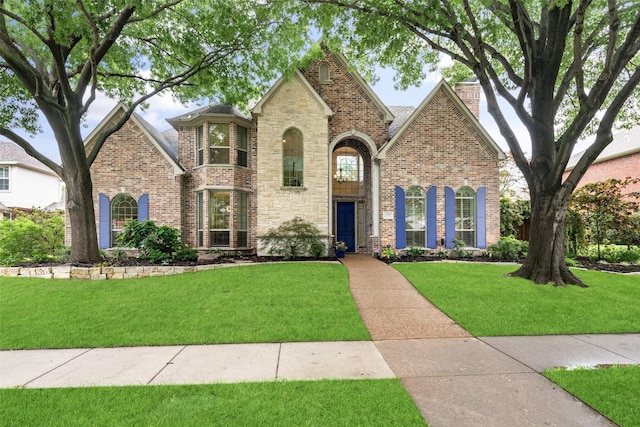 view of front of house featuring a front yard, brick siding, and a chimney