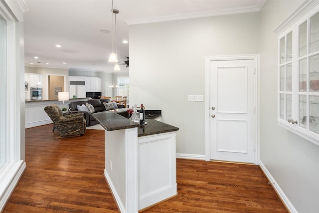 kitchen featuring stainless steel oven, white cabinetry, crown molding, a peninsula, and dark wood-type flooring