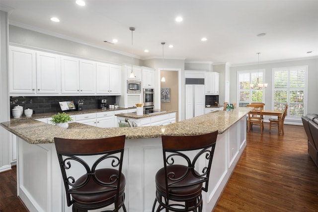 kitchen featuring ornamental molding, a spacious island, dark wood-type flooring, backsplash, and white cabinetry
