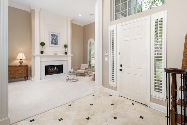 foyer with carpet flooring, baseboards, ornamental molding, tile patterned floors, and a fireplace