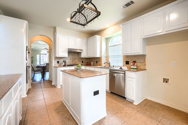 kitchen with dishwasher, under cabinet range hood, a sink, arched walkways, and white cabinetry