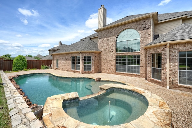 view of swimming pool featuring fence, a pool with connected hot tub, and a patio