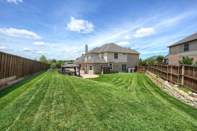 rear view of property featuring a gazebo, brick siding, central AC, a chimney, and a patio area