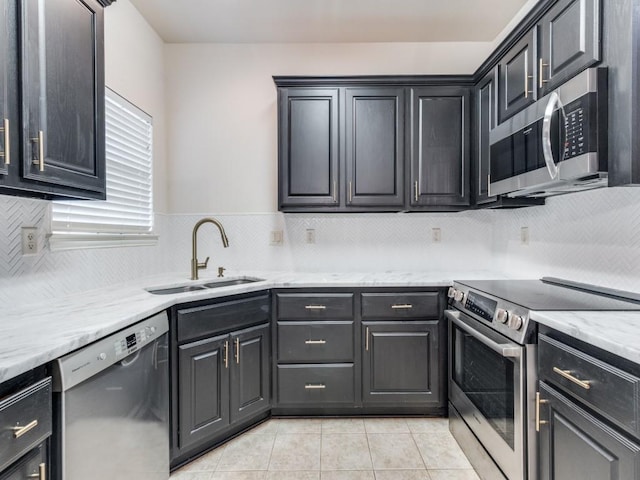 323 Emma Call Ct, Decatur, TX 76234 - kitchen with stainless steel appliances, a sink, light tile patterned floors, decorative backsplash, and light stone counters