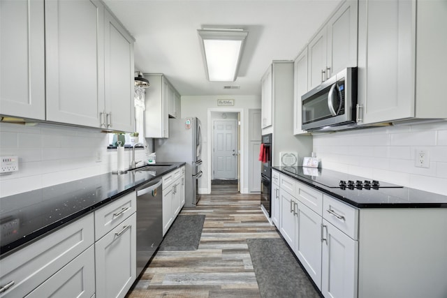 4204 Twilight Dr S, Benbrook, TX 76116 - kitchen with black appliances, tasteful backsplash, light wood-style floors, a sink, and dark stone countertops