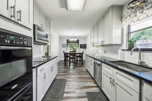 4204 Twilight Dr S, Benbrook, TX 76116 - kitchen with a sink, black appliances, decorative backsplash, dark wood finished floors, and dark stone counters