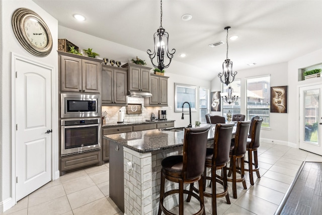 121 Quail Run Rd, Red Oak, TX 75154 - kitchen featuring appliances with stainless steel finishes, a sink, a chandelier, under cabinet range hood, and backsplash