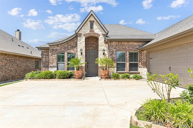 121 Quail Run Rd, Red Oak, TX 75154 - view of front of home with stone siding, driveway, brick siding, roof with shingles, and an attached garage