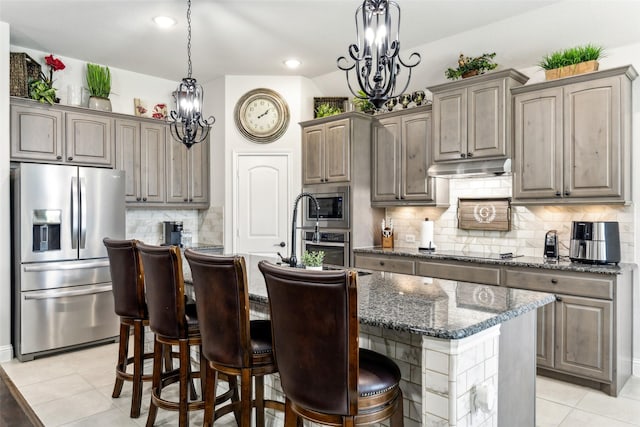 121 Quail Run Rd, Red Oak, TX 75154 - kitchen with stainless steel appliances, light tile patterned flooring, a kitchen island with sink, under cabinet range hood, and backsplash