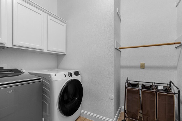 laundry area featuring cabinet space, independent washer and dryer, baseboards, and a textured wall