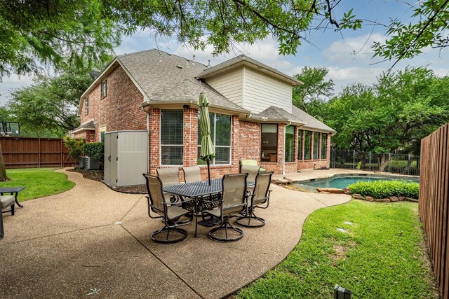 back of property featuring brick siding, a patio, a shingled roof, and cooling unit