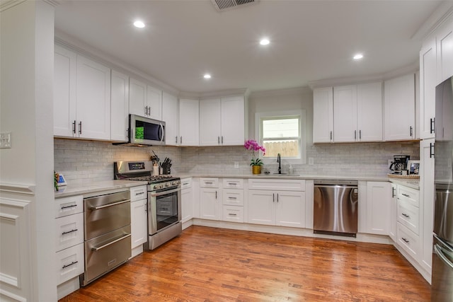 4719 Wateka Dr, Dallas, TX 75209 - kitchen with stainless steel appliances, a sink, white cabinetry, decorative backsplash, and recessed lighting