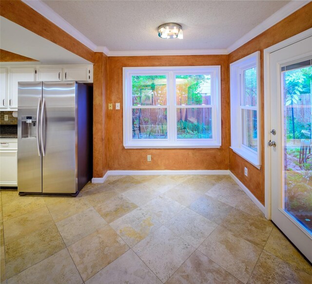 kitchen featuring stainless steel refrigerator with ice dispenser, baseboards, white cabinetry, a textured ceiling, and ornamental molding