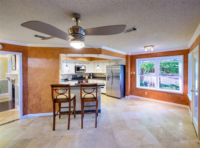 kitchen with appliances with stainless steel finishes, white cabinets, a peninsula, a ceiling fan, and crown molding