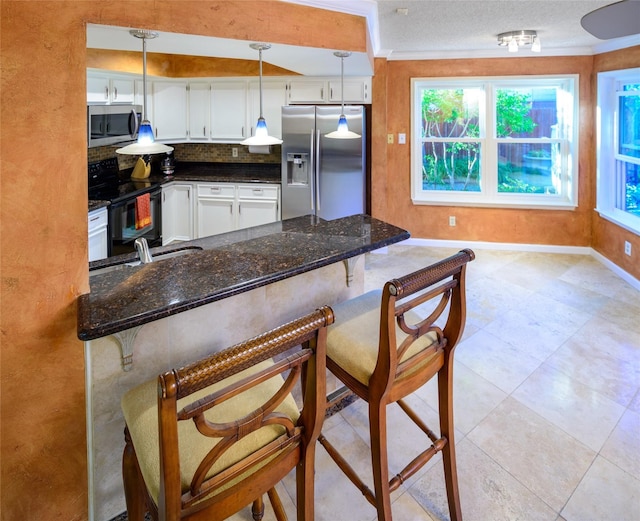 kitchen with stainless steel appliances, white cabinets, a kitchen bar, and plenty of natural light
