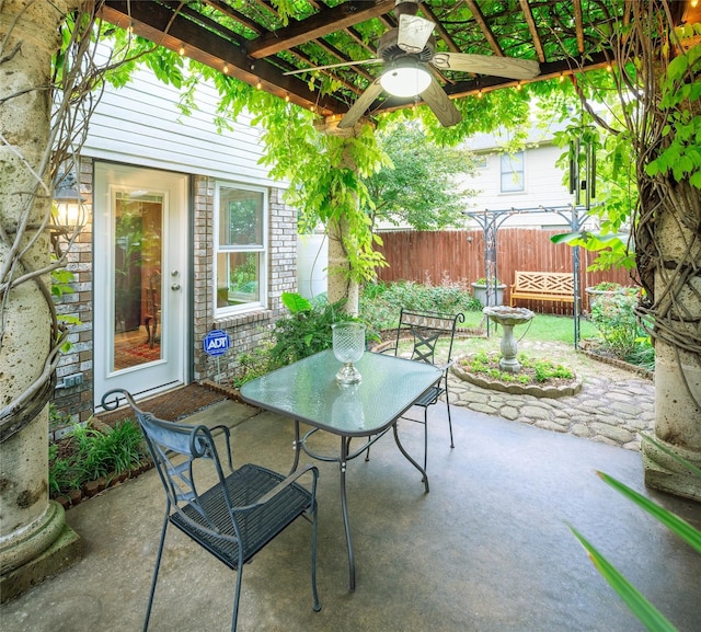 view of patio with fence, a ceiling fan, and outdoor dining area