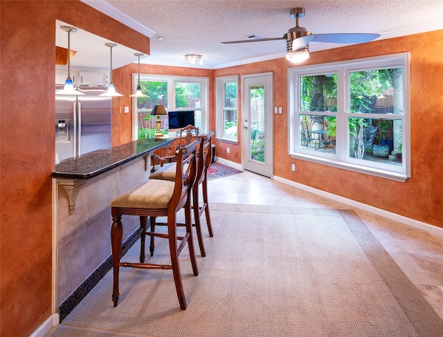 dining room featuring baseboards, ceiling fan, crown molding, and a textured ceiling