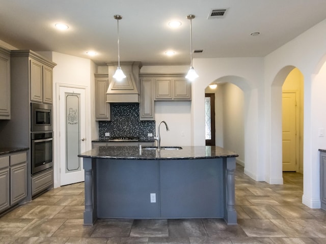 928 Freesia Dr, Little Elm, TX 75068 - kitchen with appliances with stainless steel finishes, a sink, arched walkways, custom exhaust hood, and backsplash
