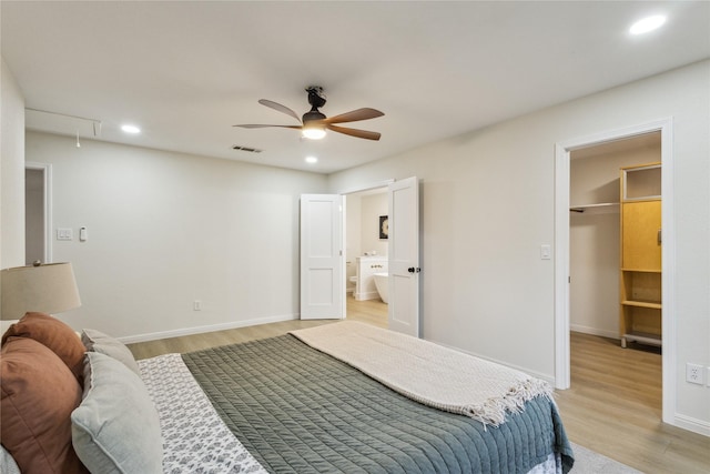 bedroom with attic access, light wood-style flooring, a spacious closet, recessed lighting, and baseboards