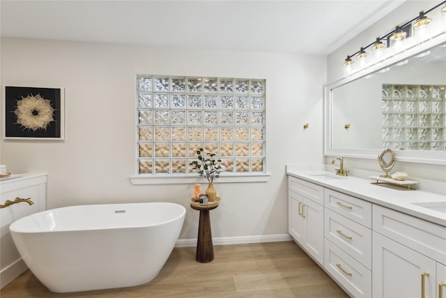 bathroom with wood finished floors, a soaking tub, and healthy amount of natural light