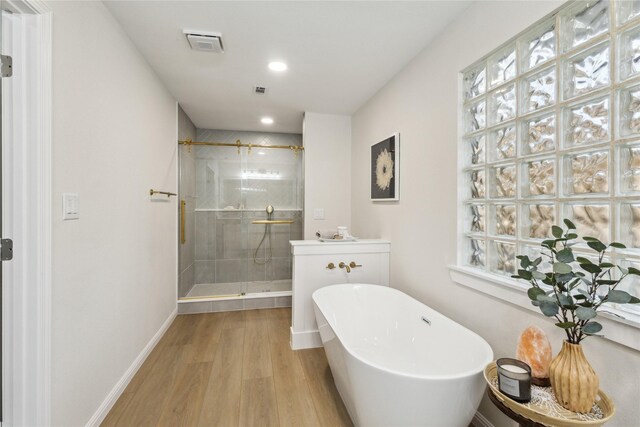 full bath featuring a shower stall, wood finished floors, a soaking tub, recessed lighting, and baseboards