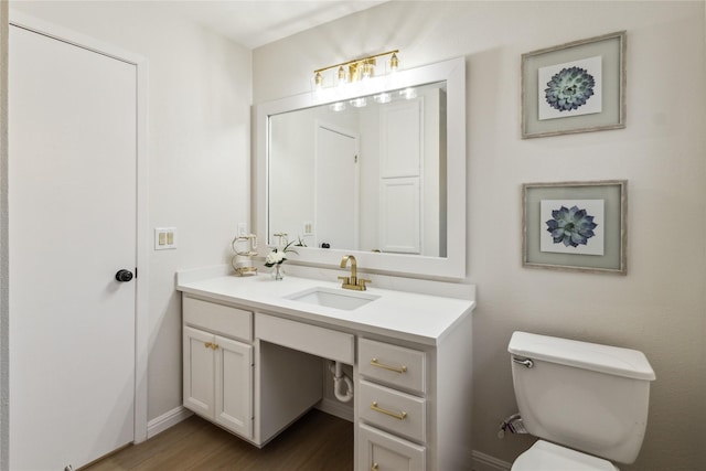 bathroom featuring wood finished floors, vanity, toilet, and baseboards