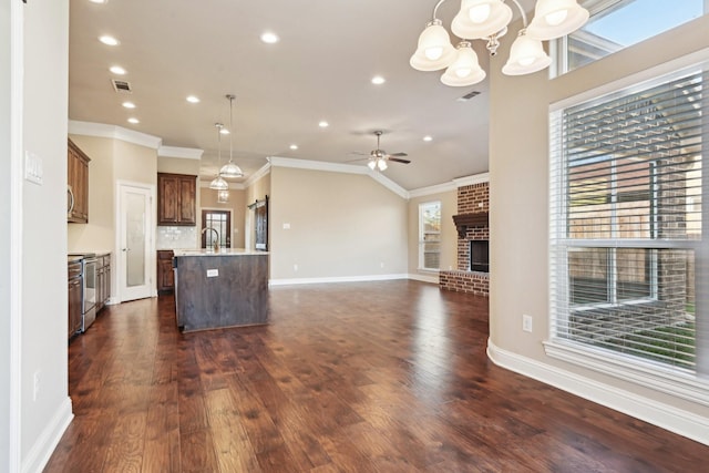 kitchen featuring a chandelier, a center island with sink, open floor plan, ornamental molding, and range