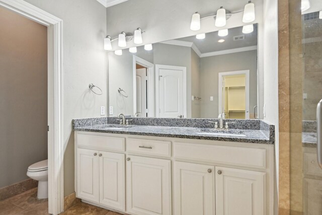 full bathroom featuring ornamental molding, toilet, double vanity, a shower stall, and a walk in closet