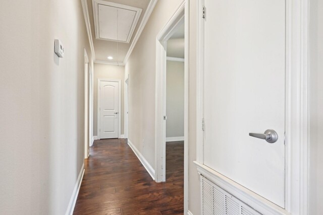 hall with attic access, ornamental molding, dark wood finished floors, and baseboards