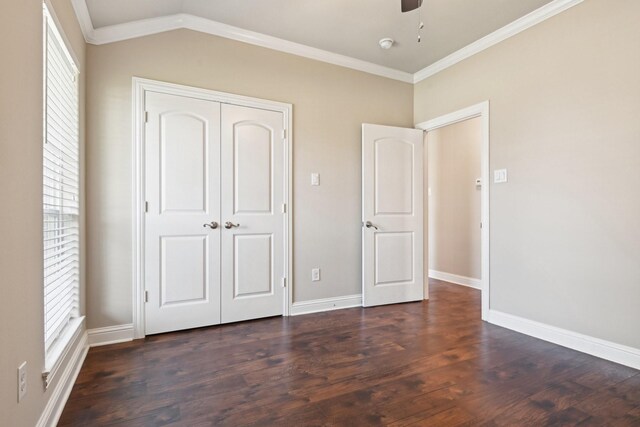 unfurnished bedroom with multiple windows, dark wood-type flooring, ornamental molding, baseboards, and a closet