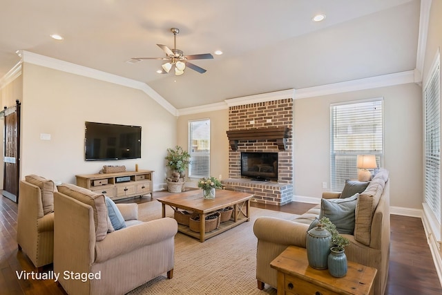 living room featuring a ceiling fan, lofted ceiling, ornamental molding, baseboards, and a brick fireplace