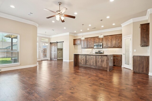 kitchen with appliances with stainless steel finishes, a barn door, ceiling fan, dark wood-style flooring, and recessed lighting