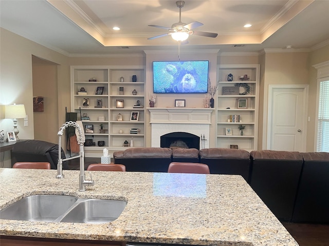 9812 Shadybrooke Dr, Shreveport, LA 71115 - living room featuring a raised ceiling, built in shelves, a ceiling fan, a fireplace, and ornamental molding
