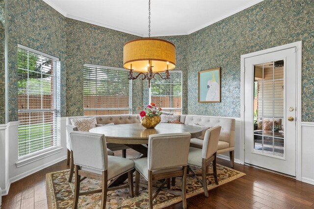 dining area with wallpapered walls, hardwood / wood-style flooring, ornamental molding, healthy amount of natural light, and wainscoting