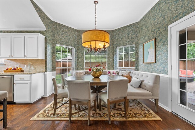 dining room featuring wallpapered walls, crown molding, dark wood-style flooring, a wainscoted wall, and a chandelier