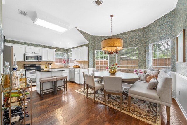 dining room with wallpapered walls, ornamental molding, dark wood finished floors, and a chandelier