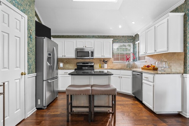 kitchen featuring appliances with stainless steel finishes, a sink, white cabinets, ornamental molding, and wallpapered walls