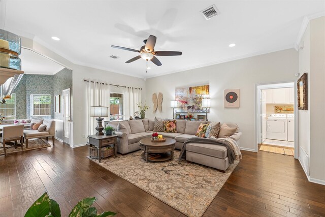 living area with ornamental molding, independent washer and dryer, a ceiling fan, dark wood-style floors, and baseboards