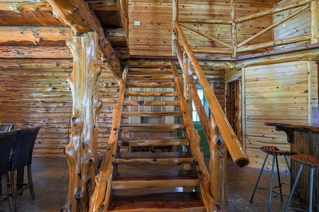 stairs with a high ceiling, rustic walls, and wood ceiling