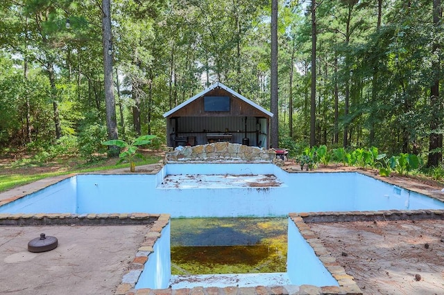 view of swimming pool featuring a swimming pool, a view of trees, and a patio