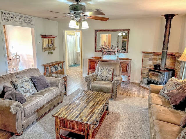 6861 County Road 4710, Larue, TX 75770 - living room with a wood stove, a ceiling fan, light wood-style flooring, and baseboards