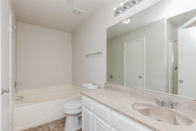 bathroom with a bath, toilet, vanity, tile patterned floors, and a textured ceiling
